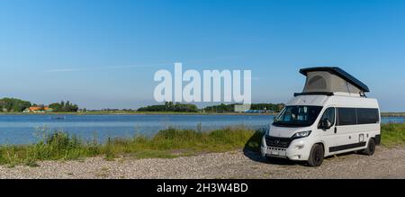 Grauer Wohnmobil parkte auf einer Schotterstraße am Meeresufer der Insel Lolland im Süden Dänemarks Stockfoto