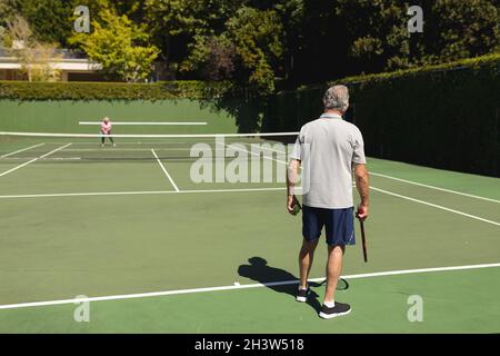 Ältere kaukasische Paare spielen gemeinsam Tennis auf dem Platz Stockfoto