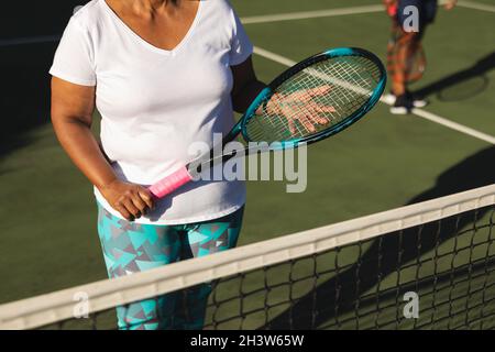 Mittelteil einer älteren afroamerikanischen Frau mit Tennisschläger auf dem Tennisplatz Stockfoto