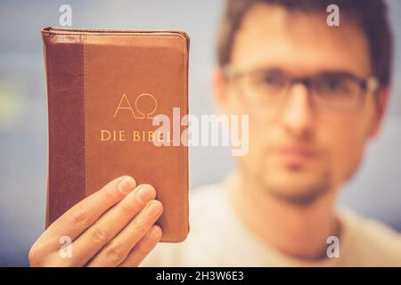 Christlicher Prediger: Junger Mann hält die bibel und betet Stockfoto