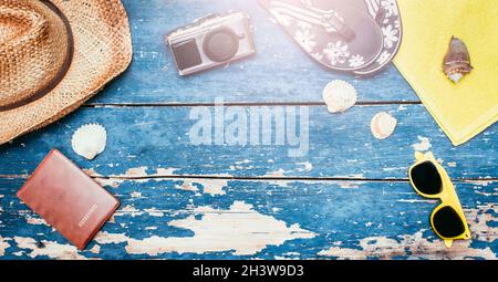 Urlaubskonzept: Vintage Holztisch mit Urlaubszubehör: Strohhut, Sonnenbrille, Muscheln, Vintage-Kamera, Pass und Flip f Stockfoto