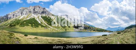 Schöne und idyllische Berglandschaft: Bergkette, See mit klarem Wasser und blauem bewölktem Himmel; Panorama Stockfoto