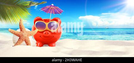 Sparschwein mit Sonnenbrille am tropischen Strand - Sommerurlaub. Stockfoto