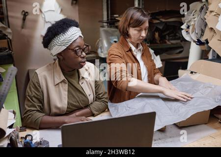 Zwei Frauen, die am Tisch sitzen und im Team arbeiten, packen in der Werkstatt Boxen Stockfoto