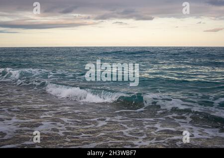 Kleine Welle stürzt an einem Strand in kristallklarem Wasser Stockfoto