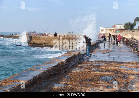 Alexandria, Ägypten - 13. Dezember 2018: An einem stürmisch-sonnigen Tag sind Fischer und einfache Menschen auf dem feuchten Pier Stockfoto