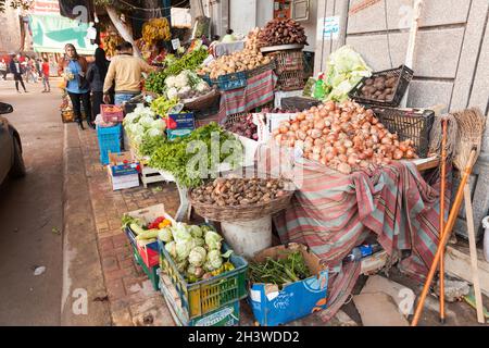 Alexandria, Ägypten - 18. Dezember 2018: Ägyptisches Obst und Gemüse befinden sich auf einer Freilufttheke. Kunden und Bauern sind in der Nähe Stockfoto