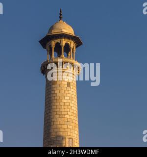 Das Minarett des Taj Mahal wird von den warmen Strahlen der aufgehenden Sonne beleuchtet Stockfoto