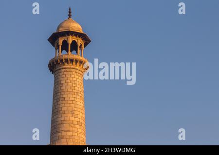 Das Minarett des Taj Mahal wird von den warmen Strahlen der aufgehenden Sonne beleuchtet Stockfoto