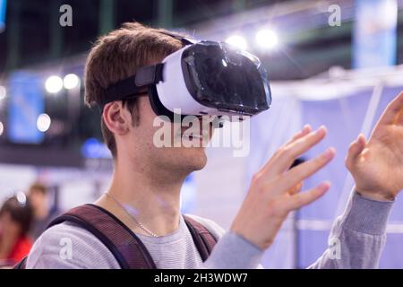 Der junge Mann, der auf einer expo eine Virtual-Reality-Brille trägt, hat Spaß Stockfoto