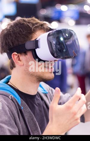 Der junge Mann, der auf einer expo eine Virtual-Reality-Brille trägt, hat Spaß Stockfoto