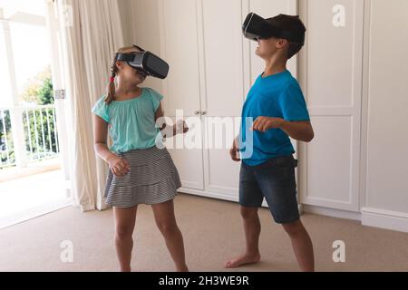 Kaukasischer Bruder und Schwester mit vr-Headsets, die zu Hause lächeln Stockfoto