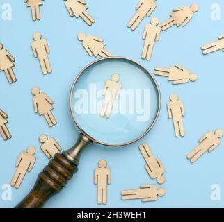 Holzmänner und eine Lupe auf blauem Hintergrund Stockfoto