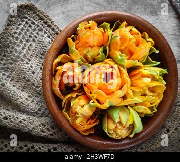 Schöne orange Tulpen in einer runden Schüssel auf einem Baumstumpf mit einem leinen Servietten Stockfoto