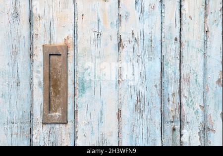 Nahaufnahme einer alten Holztür mit blauer verblassener Farbe und einem rostig geschlossenen alten Metallbriefkasten aus Messing Stockfoto
