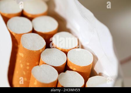 Eine Packung Zigaretten ist offen und es befinden sich mehrere Zigaretten in einer bereits unvollständigen Packung. Dies sind Filterzigaretten. Stockfoto