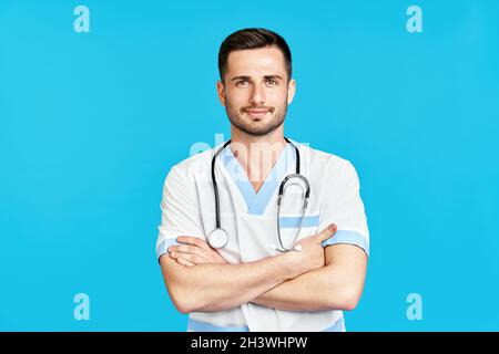 Porträt eines selbstbewussten lächelnden männlichen Arztes mit Stethoskop in medizinischer Uniform auf blauem Hintergrund. Stockfoto
