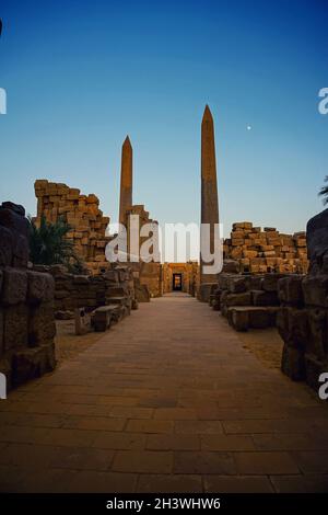 Dämmerungsbild vom Karnak-Tempel in Luxor, Ägypten. Der strahlende Mond an einem klaren blauen Himmel Stockfoto