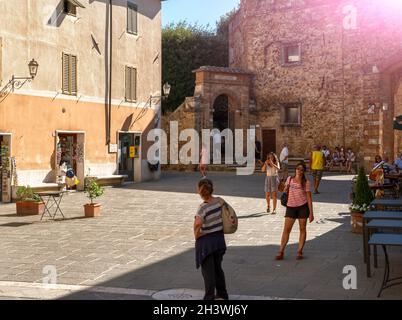 San Quirico d'Orcia, Toskana, Italien. August 2020. Die Menschen spazieren, nachdem sie durch eine der Eingangstüren in den Mauern des Dorfes kommen. Wunderschön Stockfoto