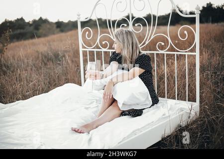 Blonde Frau, die sich auf dem Land auf dem Bett ausruht Stockfoto