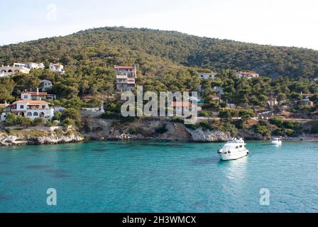 Agistri Island Griechenland Blick auf die felsigen, mit Kiefern verkleideten Küstenklippen Klarer blauer Himmel und azurblaues Meer Landschaftsaufnahme Stockfoto