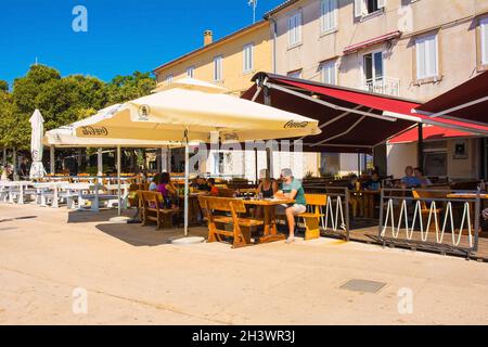 Krk, Kroatien - 2. September 2021. Die Gäste genießen Drinks und Snacks am späten Vormittag in einem Restaurant an der Küste der historischen mittelalterlichen Küstenstadt Krk Stockfoto