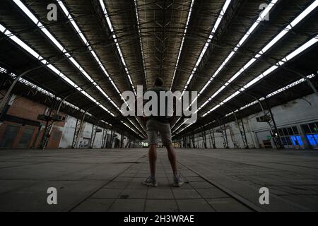 Mann, der in einer leeren Halle eines Industriegebäudes steht Stockfoto