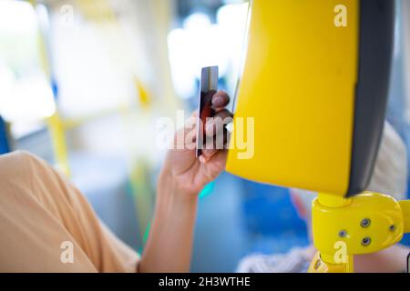 Frau Zahlung conctactless mit Smartphone für die öffentlichen Verkehrsmittel in der Straßenbahn Stockfoto