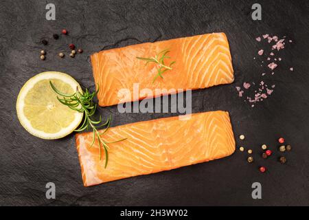 Roher Lachs mit Gewürzen auf schwarzem Hintergrund Stockfoto