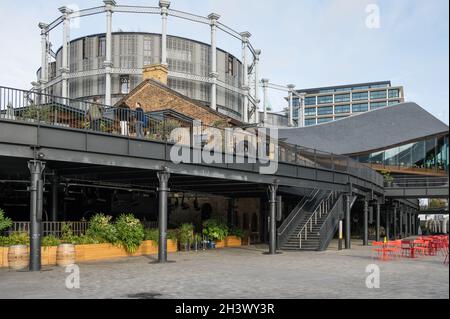 Coal Drops Yard Geschäfte und Restaurants mit dem Gashalter Wohnung Umwandlung im Hintergrund. King's Cross, London, England, Großbritannien Stockfoto