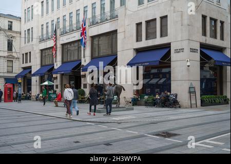 Menschen, die sich auf dem Straßenbelag vor dem Ralph Lauren-Laden, der New Bond Street, Mayfair, London, England, VEREINIGTES KÖNIGREICH Stockfoto