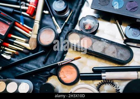 Professionelles Set zum Auftragen von Make-up mit Pinsel, Lidschatten-Palette und Mascara auf dem Tisch verstreut. Make-up Artist Set. Stockfoto