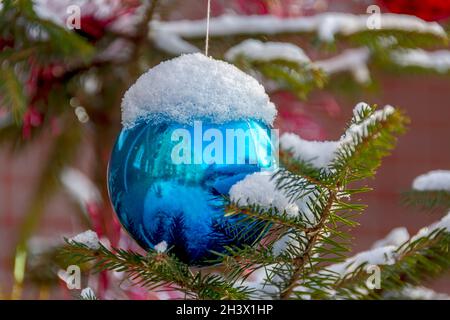 Weihnachtskugeln hängen an einem Baum, der in der Stadt in der Nähe eines Mehrfamilienhauses wächst. Stockfoto