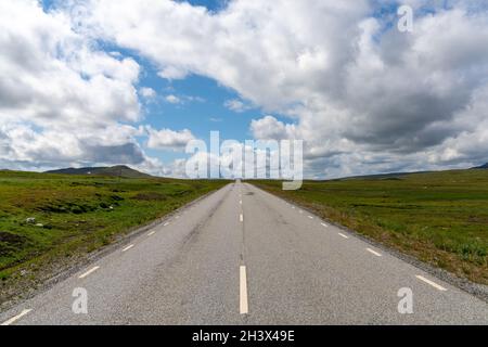 Eine asphaltierte Autobahn führt direkt zum Horizont in einer wilden Tundralandschaft Stockfoto