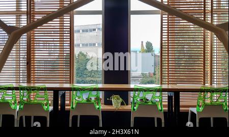 Ukraine, Kiew - 24. September 2019: Barcounter mit Fenster. Grüne Barhocker auf einer Theke einer Holztheke in der Nähe eines Windes Stockfoto