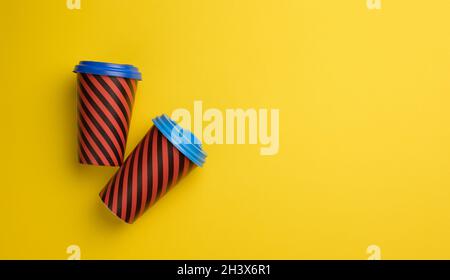 Zwei rote Pappbecher mit Kunststoffdeckel auf gelbem Hintergrund, Draufsicht Stockfoto