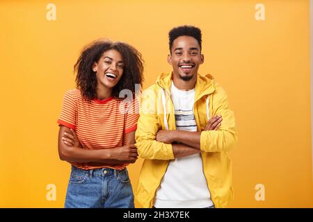 Zwei afroamerikanische Männer und Frauen, die beste Freunde sind, lachen laut und sehen sich einen lustigen Film im Kino an, alles in stilvoller Kleidung Stockfoto