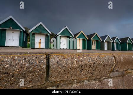 Strandhütten auf Gurnard cowes Insel wight unter dunklem stürmischen Herbsthimmel, Gurnard, cowes, Insel wight, Strandhütten, Bedrohlicher Himmel, Reihe von Strandhütten. Stockfoto