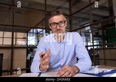 Webcam-Ansicht des kaukasischen Geschäftsmannes, der aus der Ferne mit Mitarbeitern im Büro spricht. Stockfoto