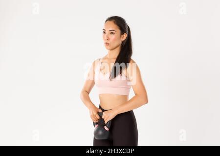 Sport, Wohlbefinden und aktives Lifestyle-Konzept. Seitenansicht der stark fokussierten asiatischen Mädchen führen Kniebeugen mit Kettlebell, Kontrolle br Stockfoto