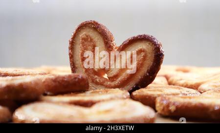 Frischer Blätterteig Palmkeks in Herzform. Klassisches französisches Gebäck. Schweinear, Elefantenohrkeks, französische Herzen. Stockfoto