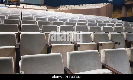 Viele alte beige Polsterstühle ohne Menschen im Saal für Aufführungen und Filme. Hintergrund von vielen Stühlen in der Stockfoto