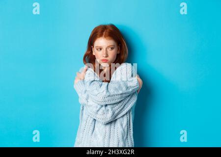 Dumm und niedlich Rotschopf Mädchen Pucker Lippen und sieht beleidigt, umarmte sich und schaut weg beleidigt, schmollend und aufgeregt Stockfoto