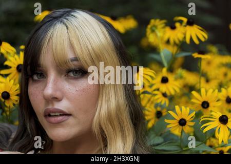 Ein schönes Brünette Model posiert in Einem Feld von gelben Blumen, während es das Sommerwetter genießt Stockfoto