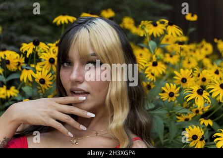 Ein schönes Brünette Model posiert in Einem Feld von gelben Blumen, während es das Sommerwetter genießt Stockfoto