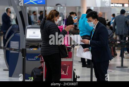 Mississauga, Kanada. Oktober 2021. Ein Mitarbeiter mit einer Gesichtsmaske hilft einem Reisenden am 30. Oktober 2021, die erforderlichen Dokumente am internationalen Flughafen Toronto Pearson in Mississauga, Ontario, Kanada, zu überprüfen. Ab Samstag müssen Reisende, die mindestens 12 Jahre alt sind, nachweisen, dass sie während ihrer Reisen innerhalb Kanadas oder im Ausland vollständig gegen COVID-19 geimpft wurden. Quelle: Zou Zheng/Xinhua/Alamy Live News Stockfoto