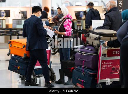 Mississauga, Kanada. Oktober 2021. Eine Reisende mit Gesichtsmaske zeigt einem Mitarbeiter am Toronto Pearson International Airport in Mississauga, Ontario, Kanada, am 30. Oktober 2021 ihr COVID-19-Impfzertifikat. Ab Samstag müssen Reisende, die mindestens 12 Jahre alt sind, nachweisen, dass sie während ihrer Reisen innerhalb Kanadas oder im Ausland vollständig gegen COVID-19 geimpft wurden. Quelle: Zou Zheng/Xinhua/Alamy Live News Stockfoto