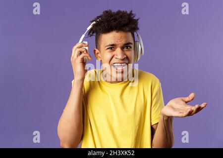 Was willst du, ich bin in Kopfhörer. Porträt von verwirrt verärgert jungen Mann zuckend, nehmen-aus-Kopfhörer zu hören, welche Person als Stockfoto