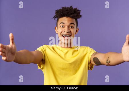 Nahaufnahme Porträt des freundlichen, fröhlichen jungen hispanischen Hipster Kerl, der die liebsten Gäste herzlich willkommen heißt, die Hände seitwärts f Stockfoto