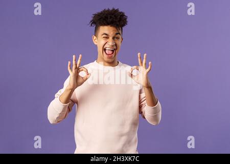 Portrait of chill junge entspannt gutaussehende Mann versichern alles gut, sagen alle in Ordnung, lächelnd und zwinkert, empfehlen ehrfürchtigen Profi Stockfoto